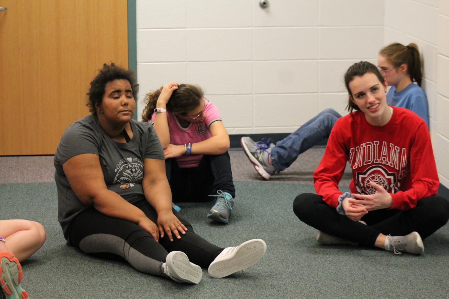 Senior Katie Jones and junior Erin Sims participate in cool down stretches after unified track practice (Photo by Adam Crozier).