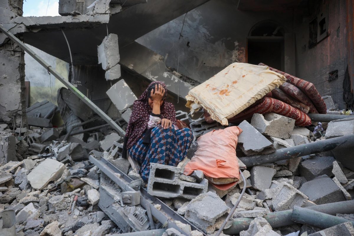 Woman sits amongst rubble in Gaza.